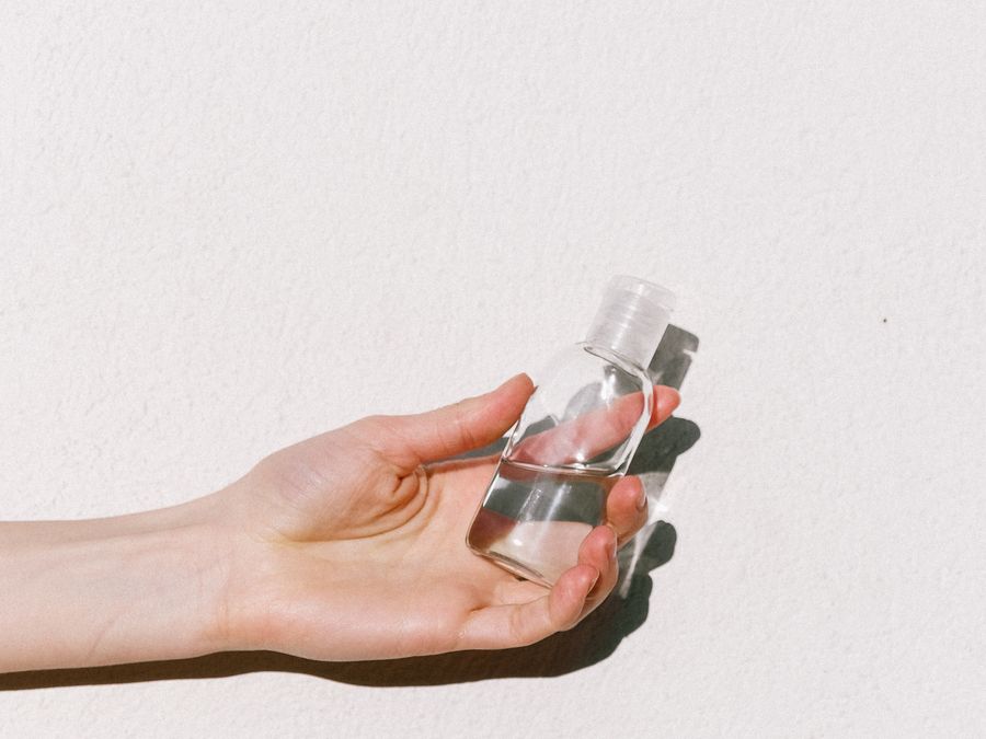 A hand holding a small clear travel-size bottle